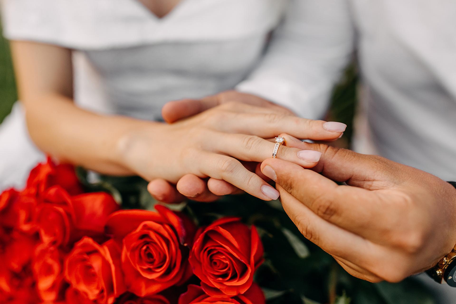 Close up of man putting a ring on woman's finger. Engagement con